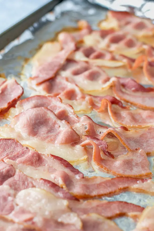 Partially baked bacon on a foil wrapped pan for the bacon wrapped shrimp