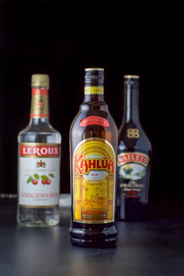 Kahlúa, cherry brandy and Baileys on a black table