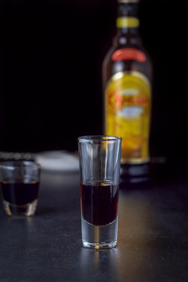 Kahl&uacute;a layered in the glasses with the bottle and spoon in the background
