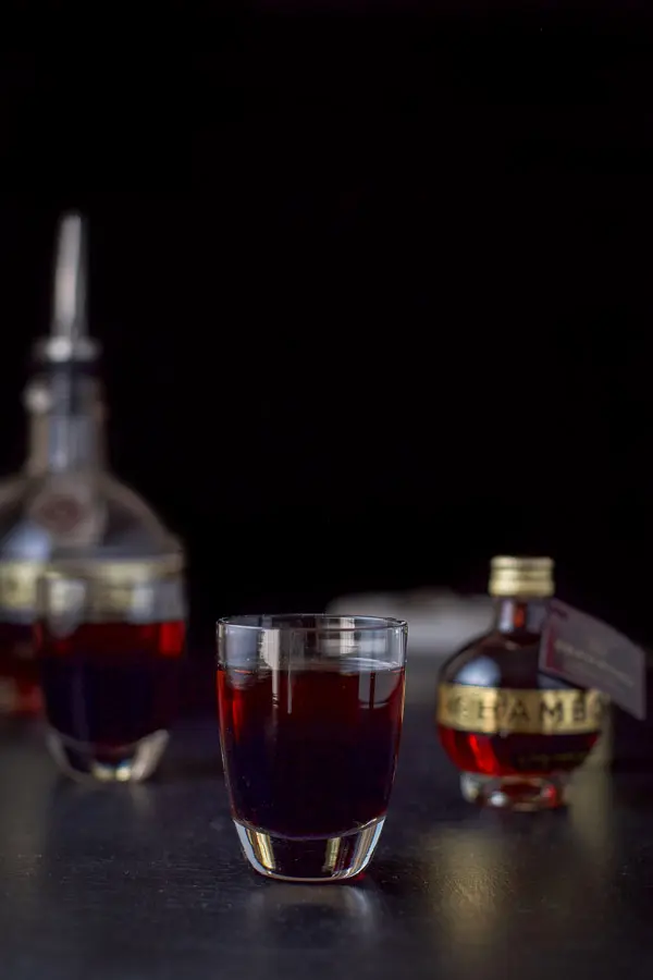 Chambord layered into the shot glasses with the bottle in the backgound