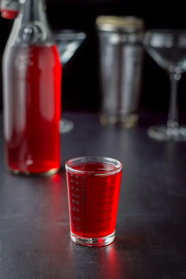 Cranberry vodka poured out with the bottle in the background along with the glasses and shaker