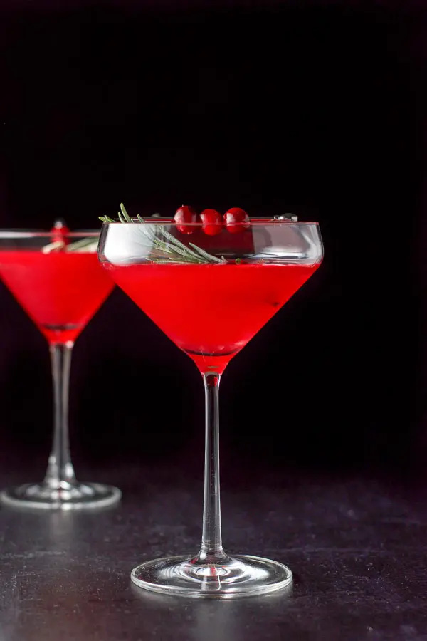 Vertical view of the cosmo with cranberries and rosemary as garnish
