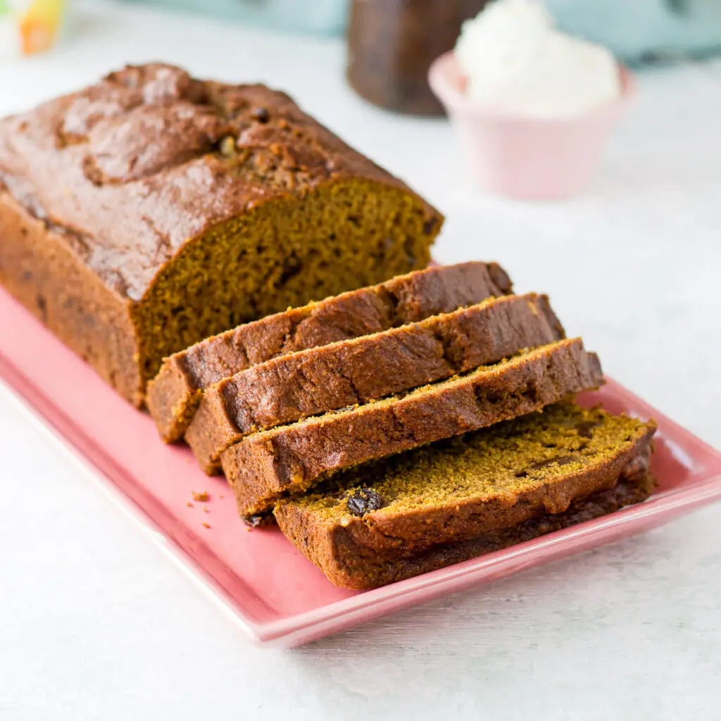pumpkin bread on a pink plate sliced in pieces - square