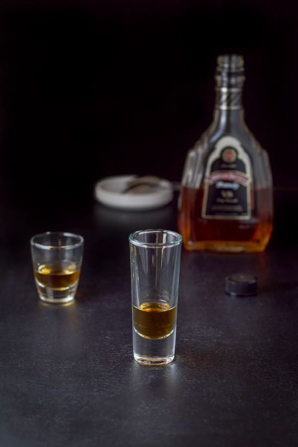 Brandy poured into the glasses with the bottle in the background
