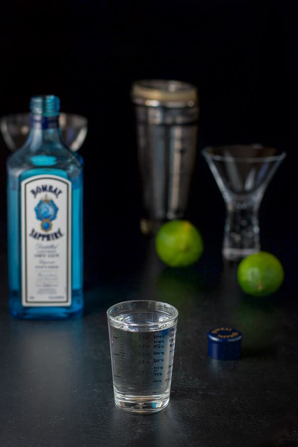Gin measured out with the bottle, shaker and glasses in the background