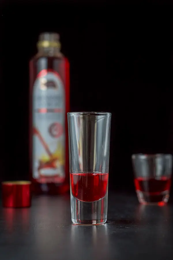 Grenadine poured into the shot glasses with the bottle in the background