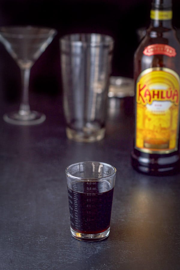 Kahl&uacute;a poured out with the bottle in the background along with the shaker and glass
