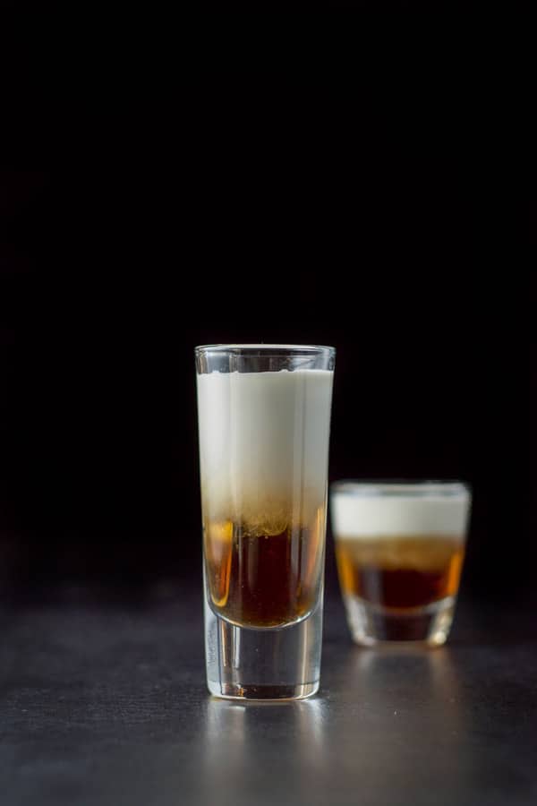 Vertical view of the tall glass filled with the three layers with the short glass in the background