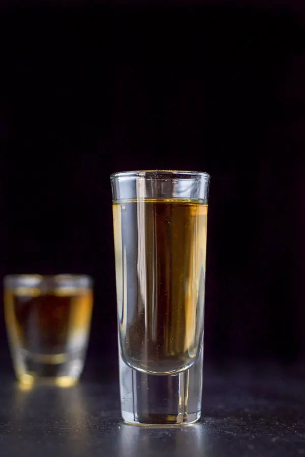 A short glass behind a tall glass filled with the layered shot