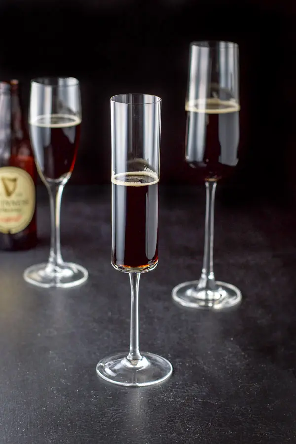 Guinness poured in the three champagne glasses with the bottle in the background