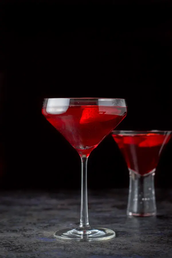 The red martini poured into two martini glasses - the taller glass in front and the bubble glass in back
