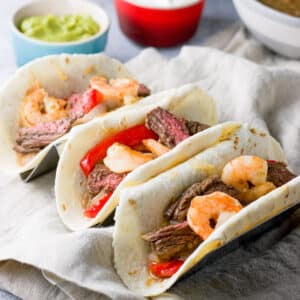 Square photo of 3 flour tortillas filled with shrimp and steak fajitas