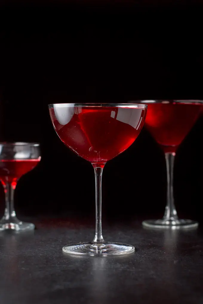 Vertical view of the red cocktail, bowl glass in front of a classic martini glass and coupe
