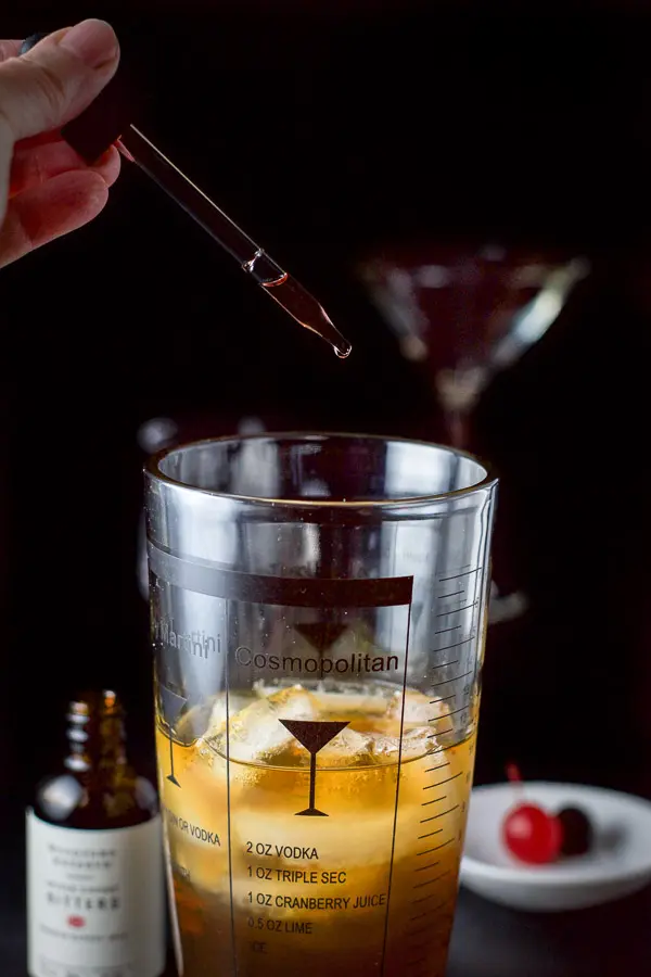Bitters being dripped into the cocktail shaker with the Manhattan in it