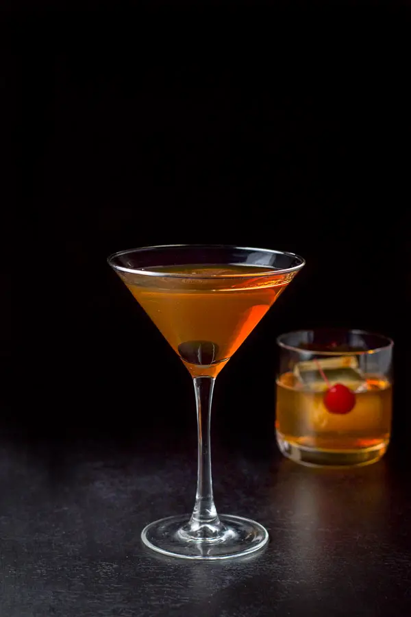 Martini glass in front with the short glass behind filled with the Manhattan