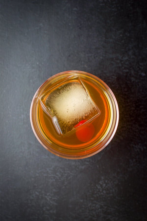 Overhead view of the cocktail with a big ice cube and red cherry