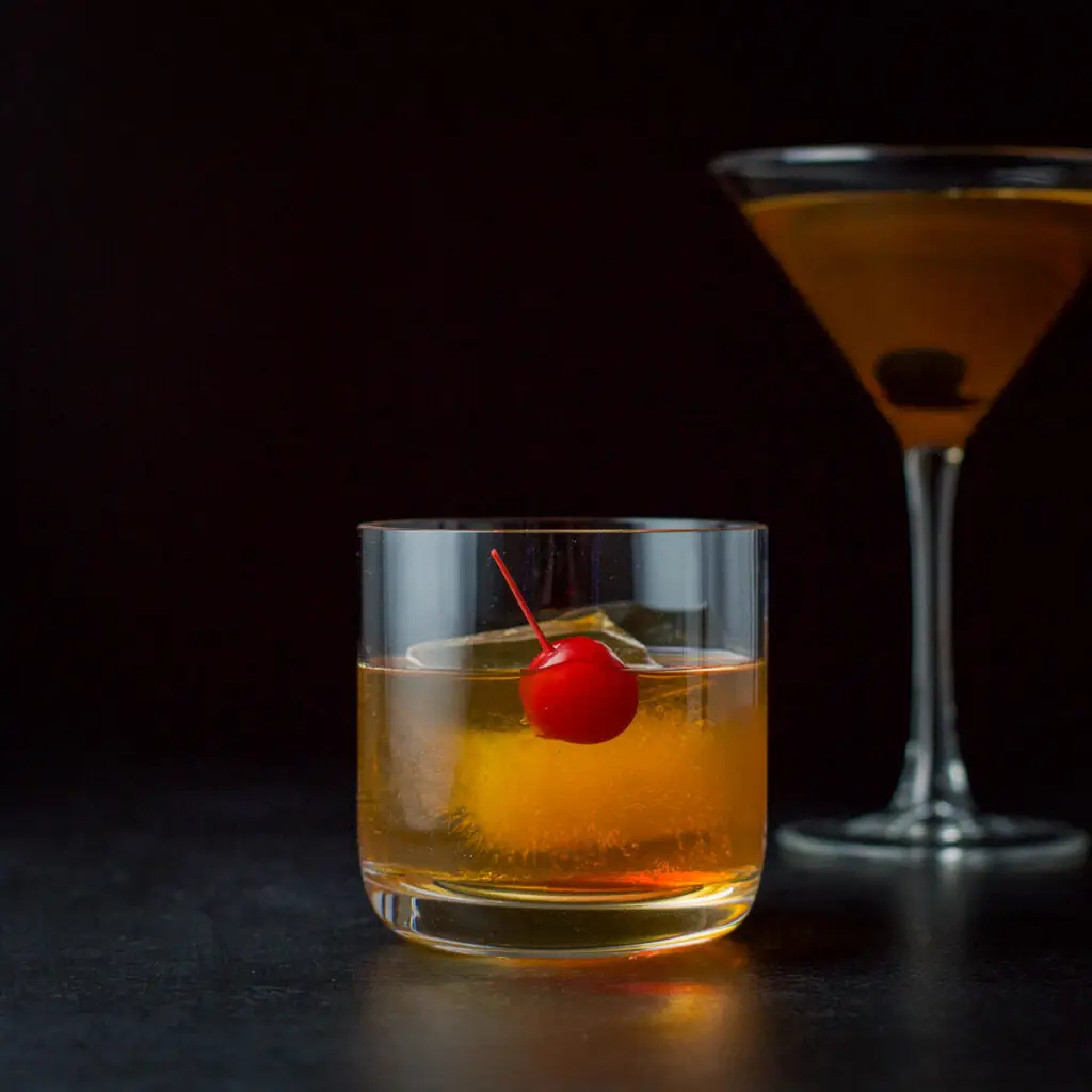 Vertical view of the short glass with a red cherry and the cocktail - square