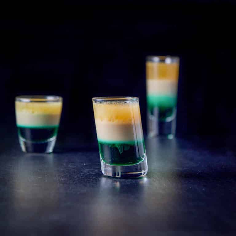 Vertical view of the tilted glass in front of the other two. They are filled with the three layered shot - square