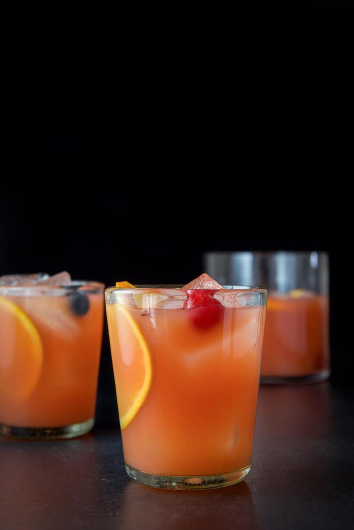 Vertical view of the glasses filled with the scorpion bowl with cherries and oranges clearly showing
