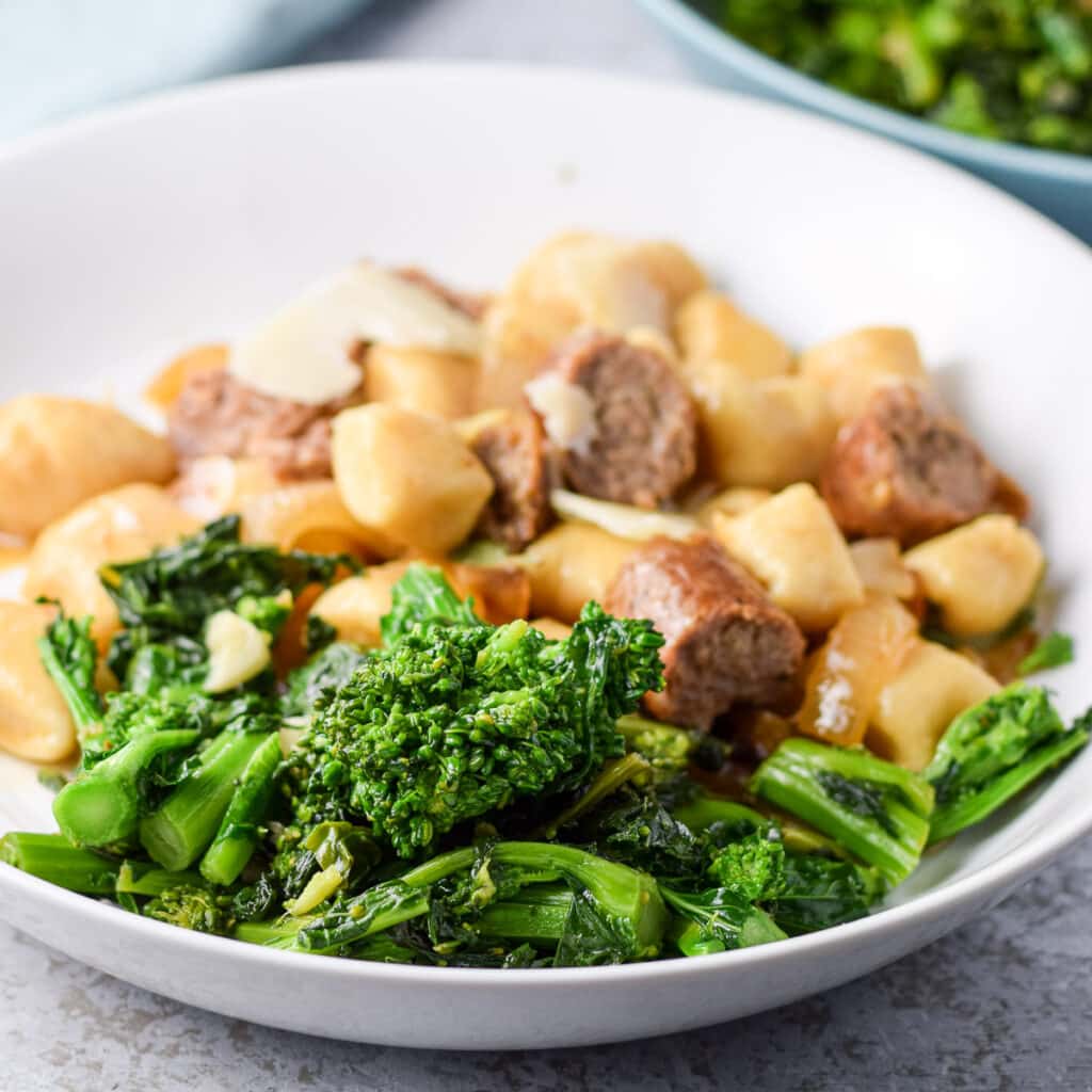 Rabe with some gnocchi and sausage in a white deep dish - square