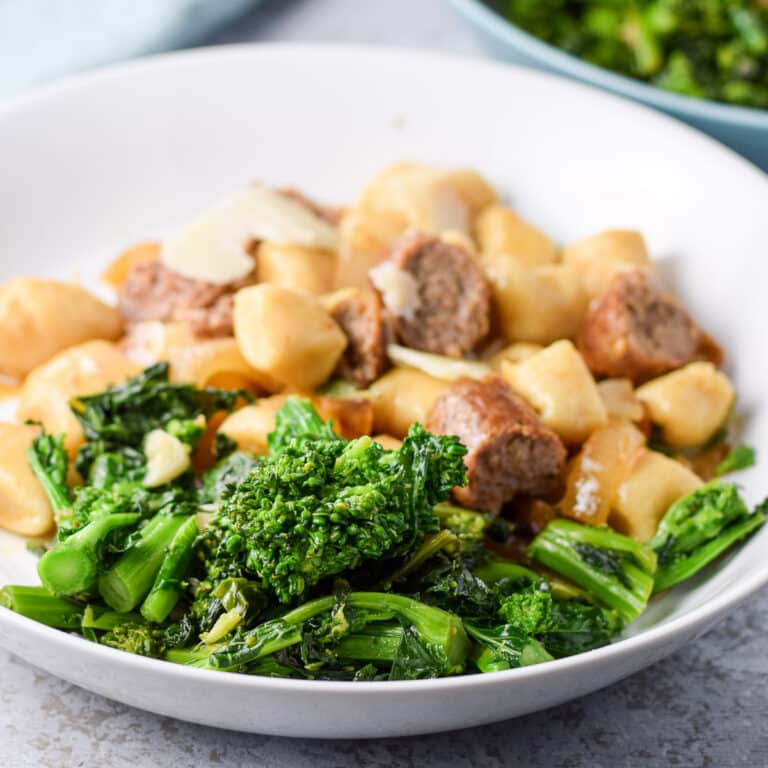 Rabe with some gnocchi and sausage in a white deep dish - square