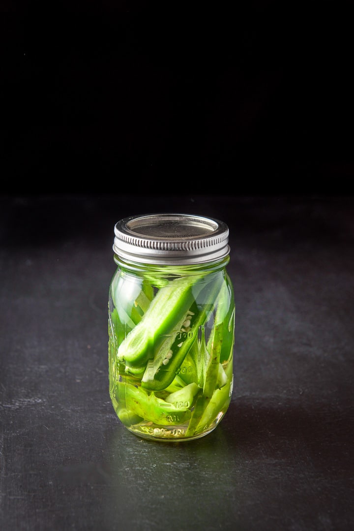 Jalapeños placed in the jarred tequila with the top screwed on