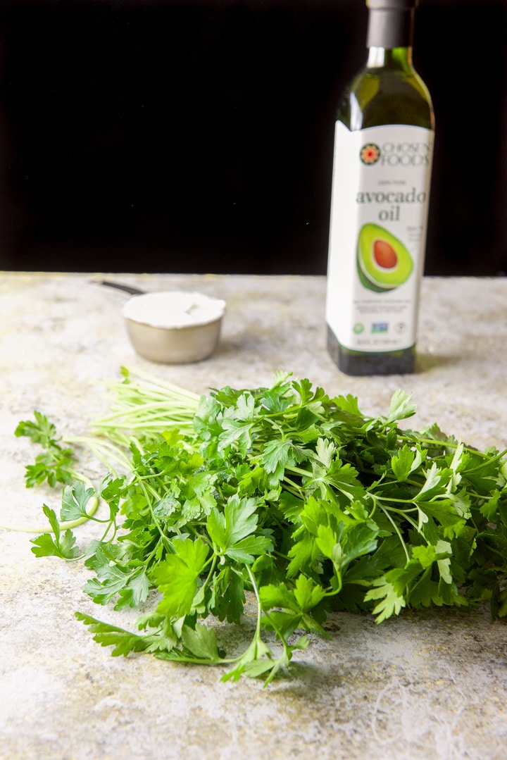 Parsley, yogurt and avocado oil on a yelllowish table