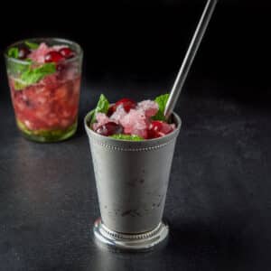 Metal cup filled with the cherry mind drink with the clear glass in back - square