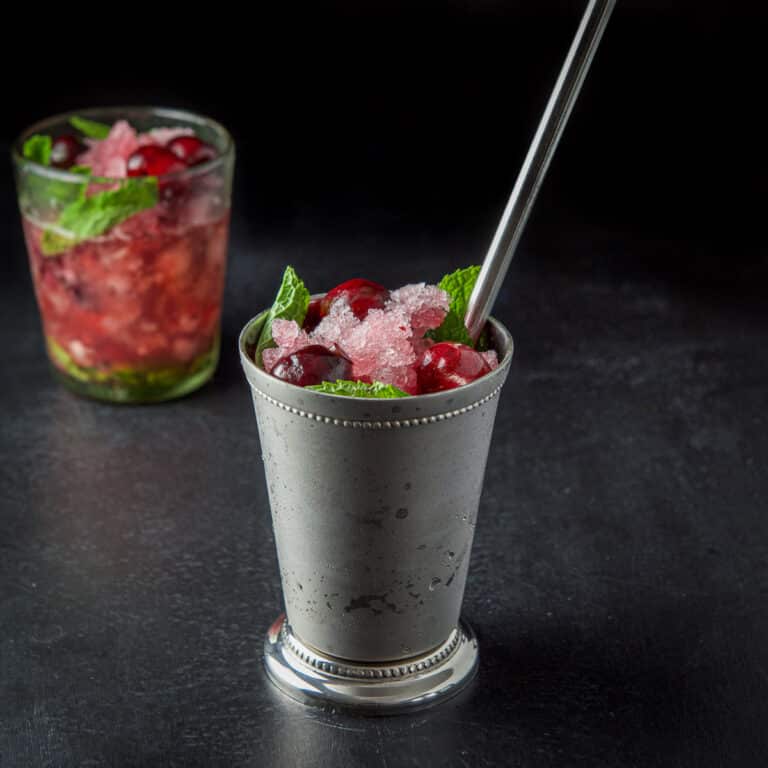 Metal cup filled with the cherry mind drink with the clear glass in back - square