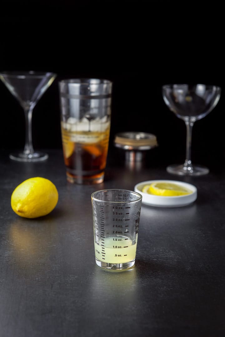 Lemon poured out with the lemon, lemon wheels for garnish, shaker and glasses