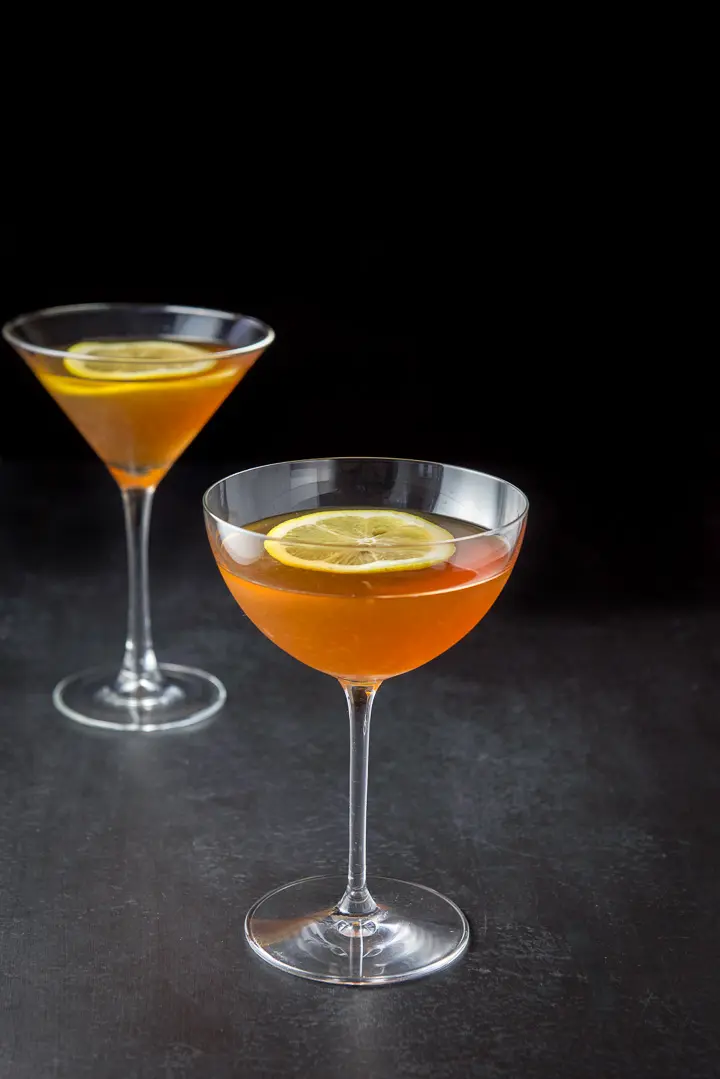 The amber cocktail poured into two martini glasses