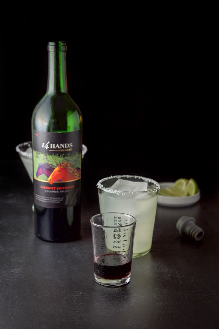 Wine poured out with the margarita in the salted glasses and lime chunks in the background