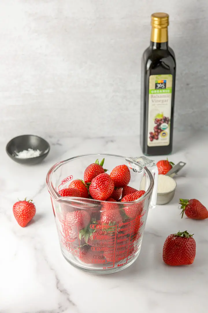 Strawberries in a measuring glass, sugar, corn starch and balsamic vinegar on a table