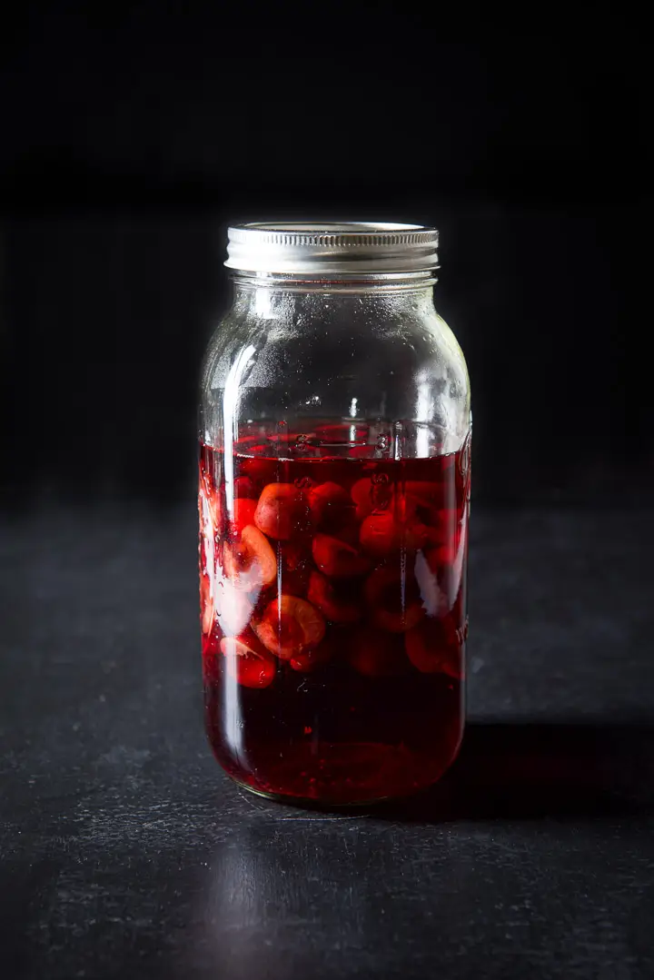 64 ounce jar with bourbon and cherries floating in it