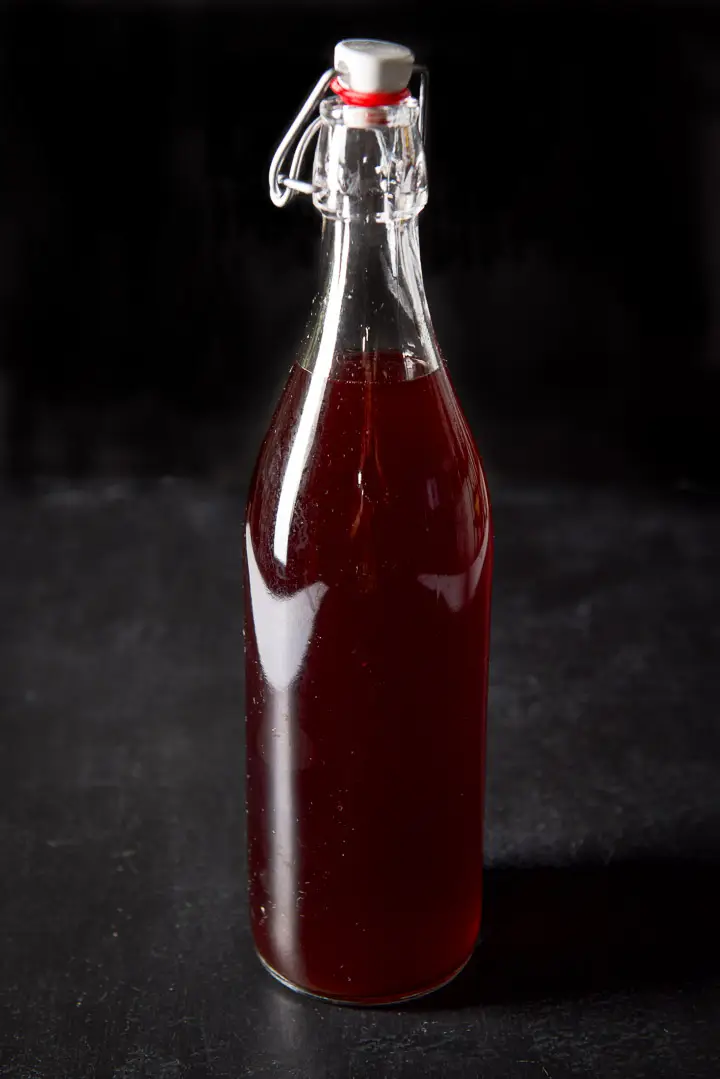 A bottle of bourbon flavored with cherries on a black table