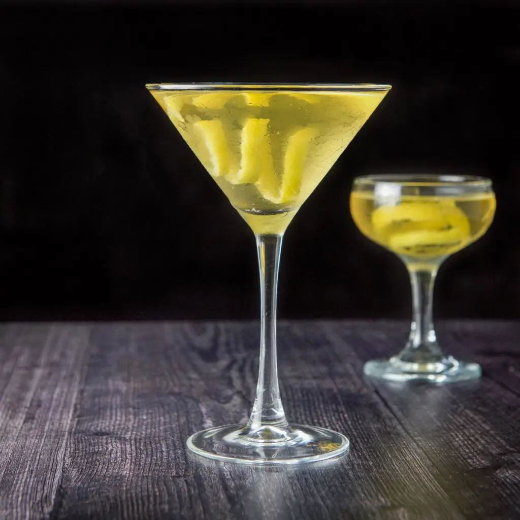 The classic martini glass filled with the cocktail with lemon twists in it - square