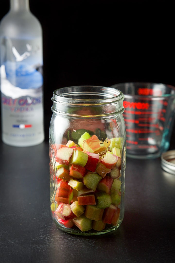 Cut up rhubarb in a jar with vodka in the background