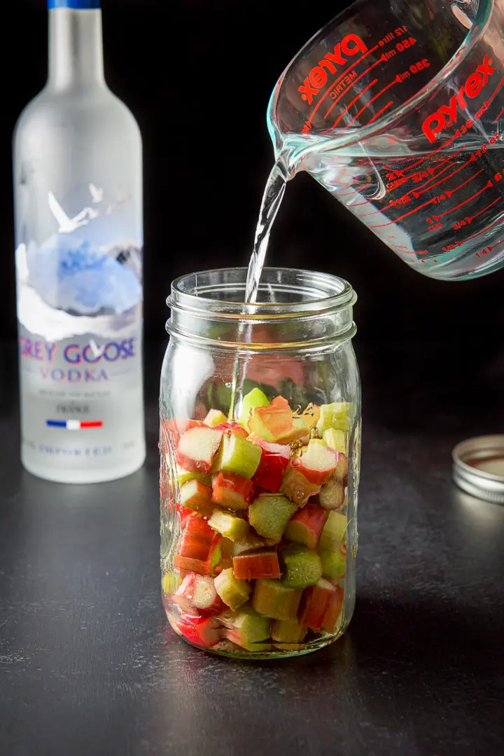 Vodka being poured over the rhubarb into the jar