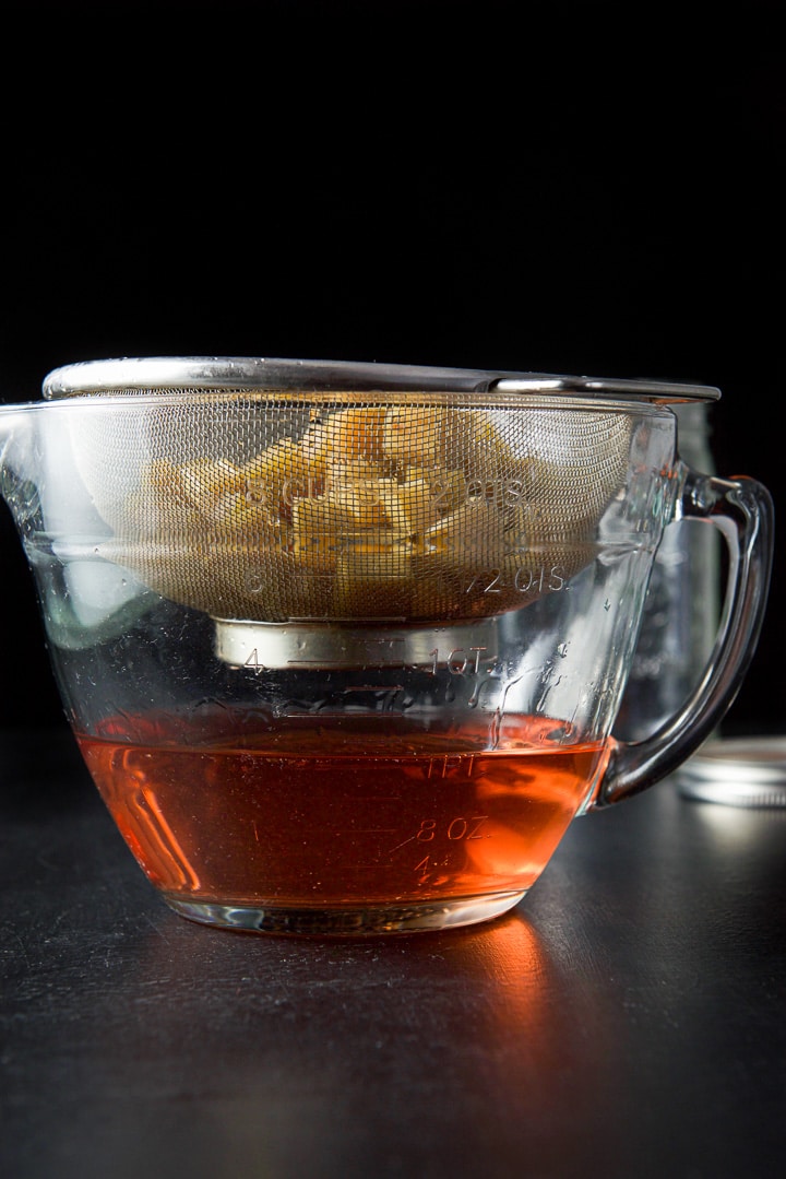 Rhubarb in a sieve draining with the rhubarb vodka under it