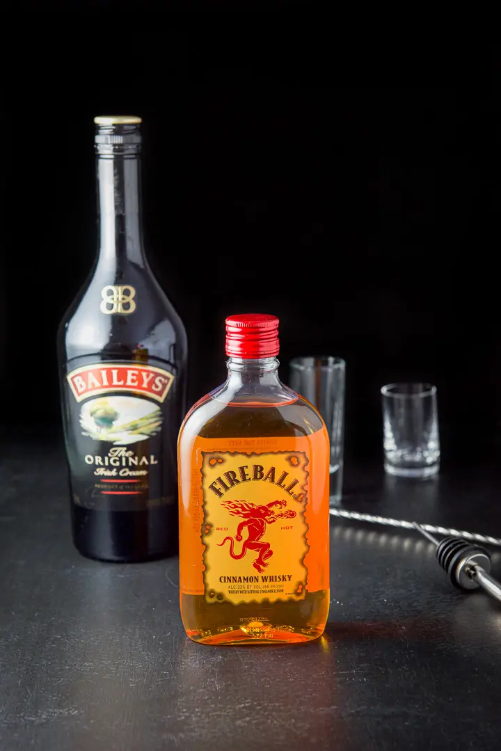 Fireball whiskey and Baileys Irish cream along with a pourer, spoon and glassware on the table