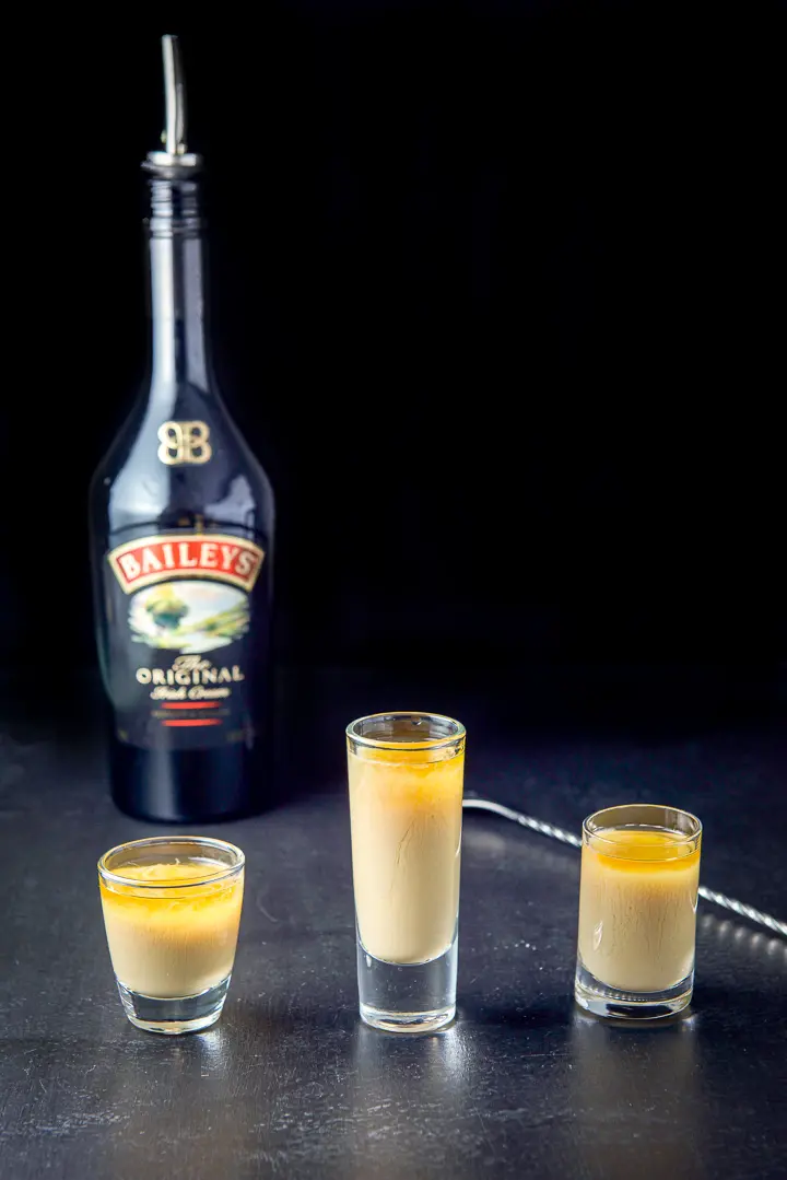 Irish cream layered into the glasses with the spoon and bottle in the background
