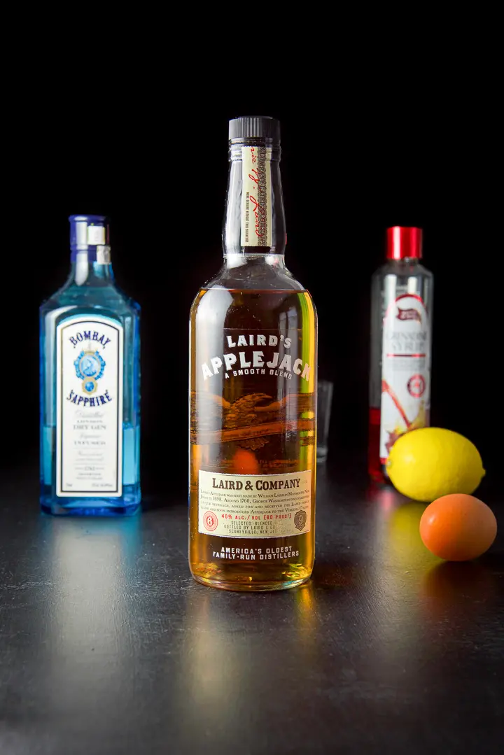 AppleJack liquor, gin, grenadine, lemon and egg on the black table