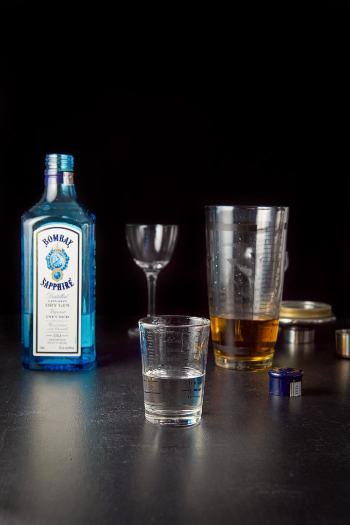 Gin measured out with the bottle, glasses and shaker in the background