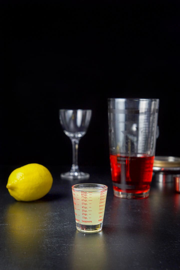 Lemon juice measured out with the lemon, shaker and glass on the table