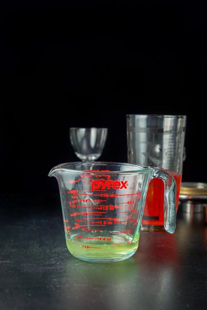 Egg white in a measuring glass with the shaker in the background