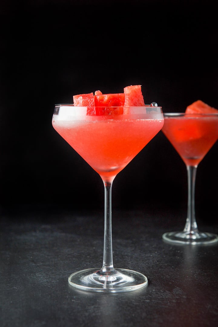 Vertical view of the fancy martini glass filled with the cosmo with watermelon chunks garnishing them