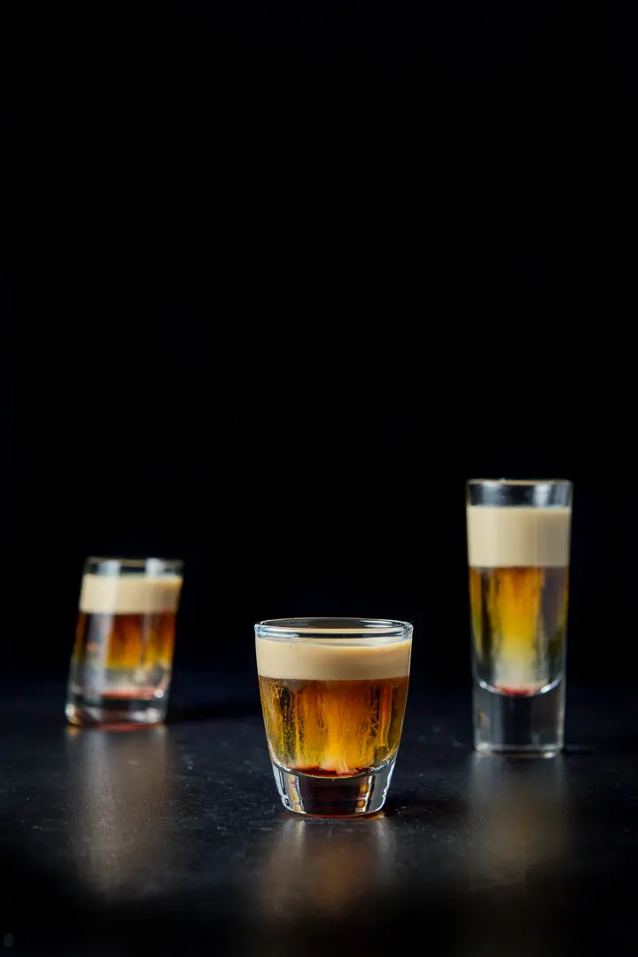 The short glass in front filled with the layered shot in front of the two other glasses