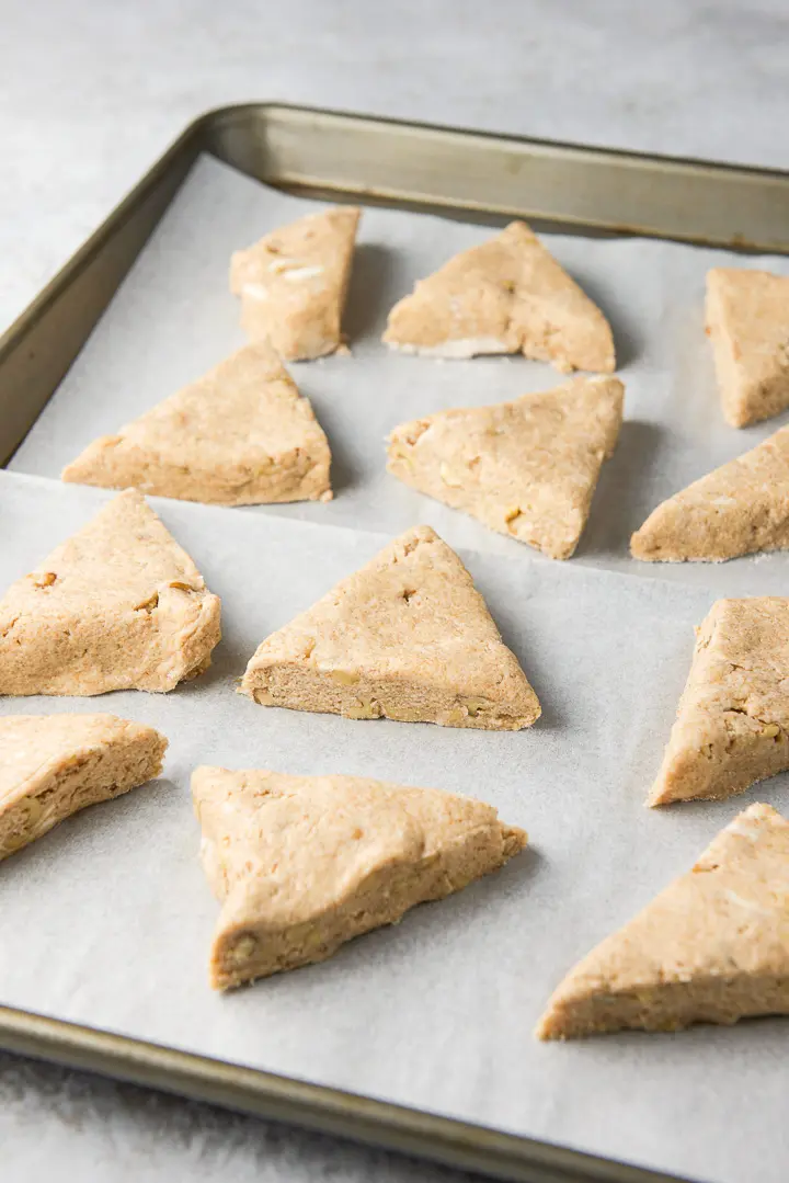 The scones dough cut into triangles and placed on a parchment paper jelly roll pan