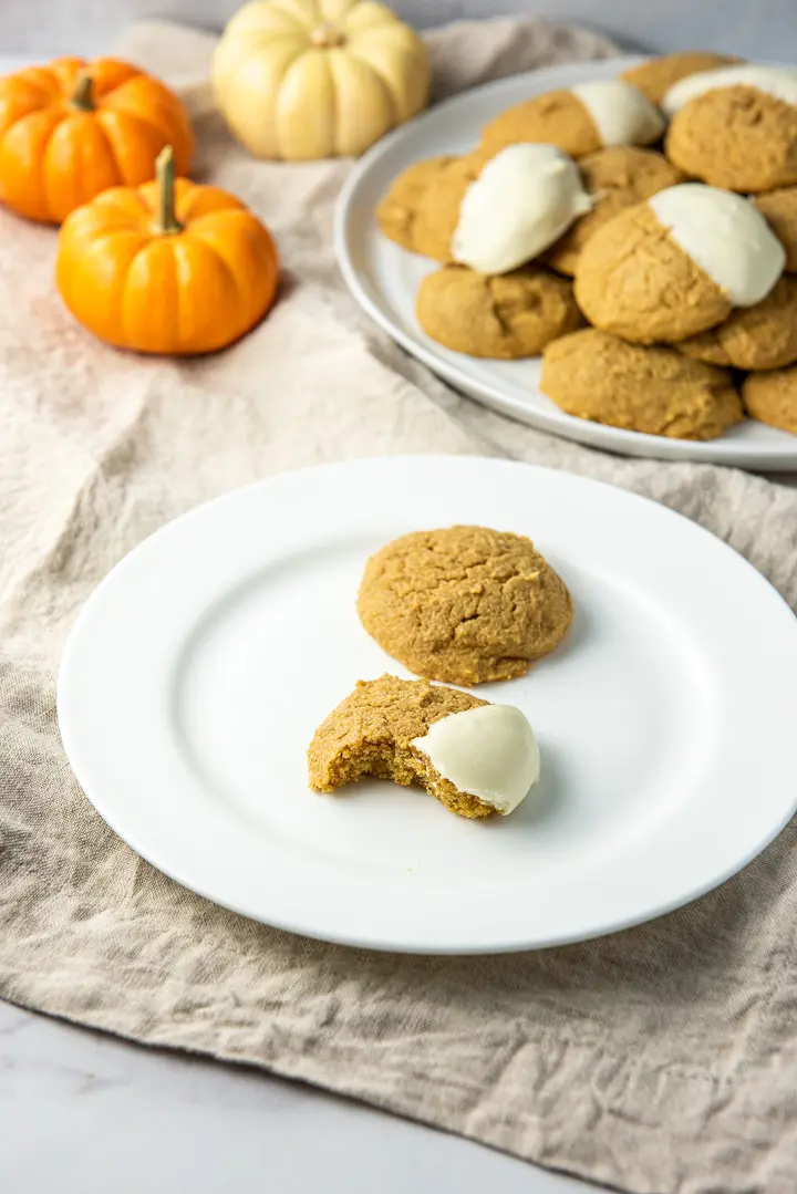 One of the cookies with a bite taken out of it and on a plate with a whole one behind it