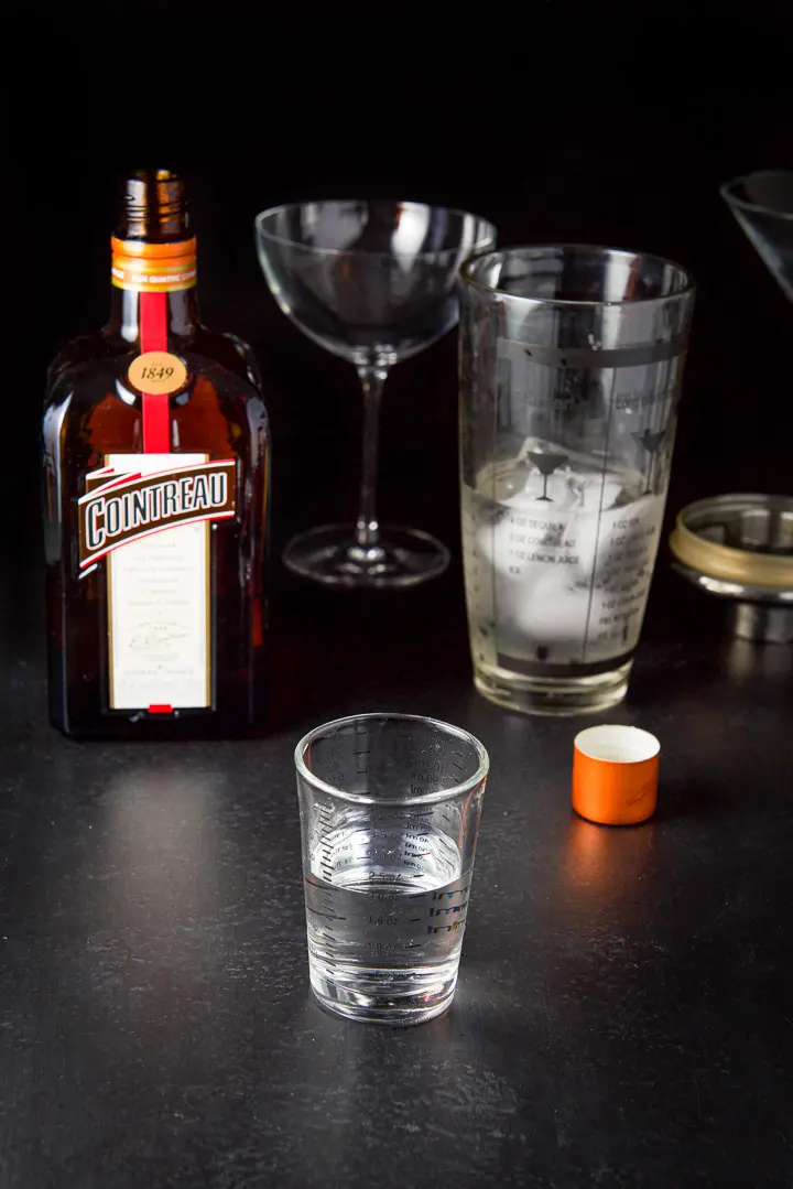 Cointreau poured with the bottle, shaker and glasses in the background